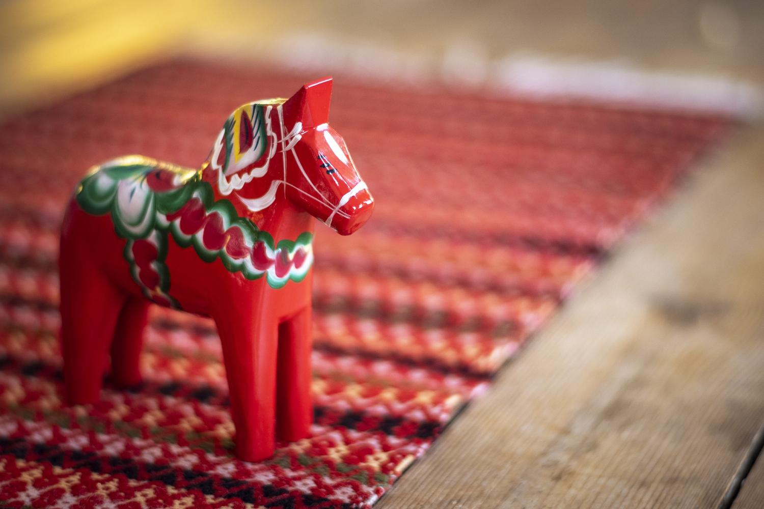 Ein rotes Dala-Pferd auf einem farbigen Tischläufer.