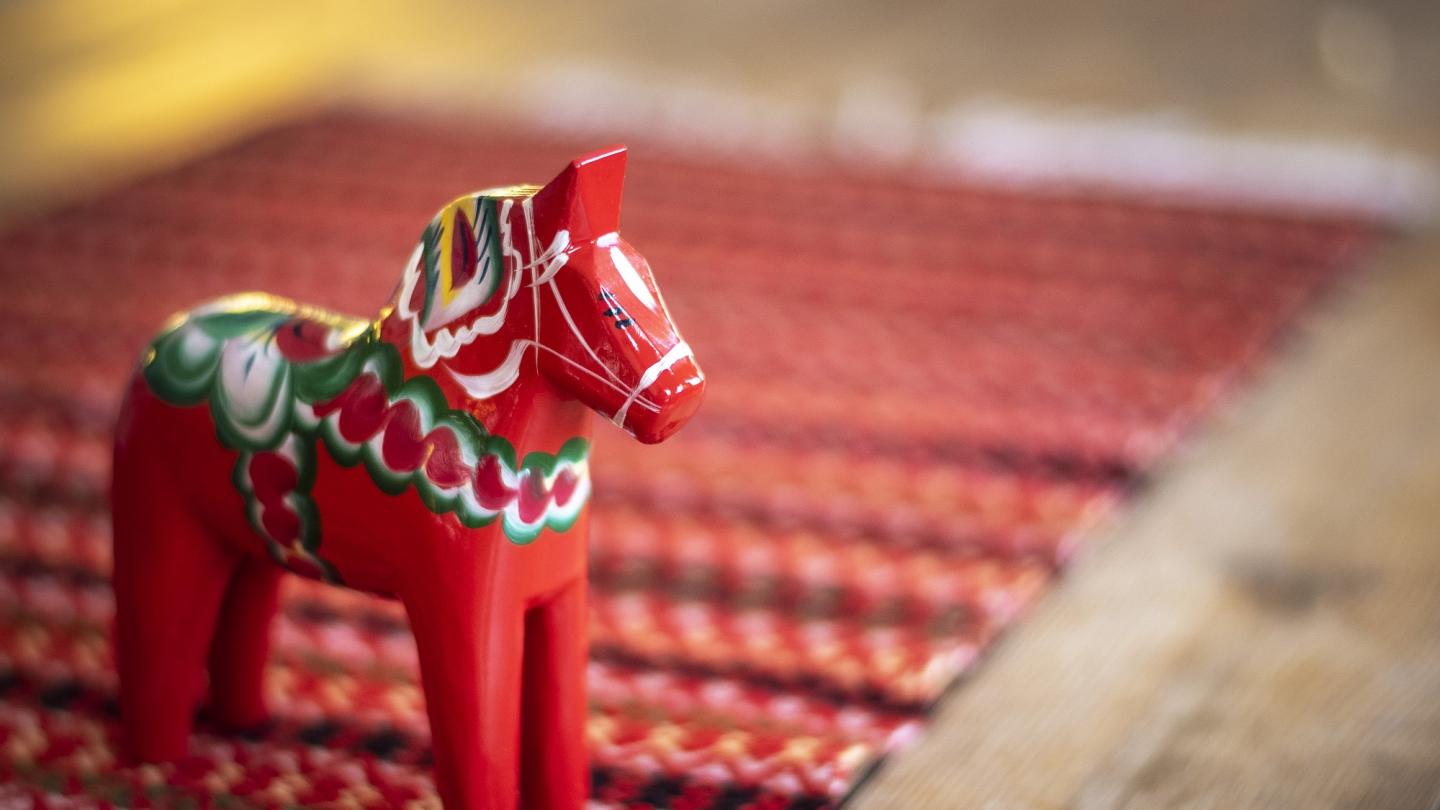 Ein rotes Dala-Pferd auf einem farbigen Tischläufer.