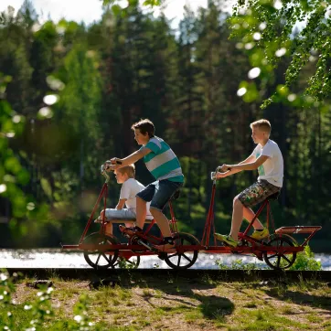 Tre gutter på en dresinsykkel ved vannet i Vansbro